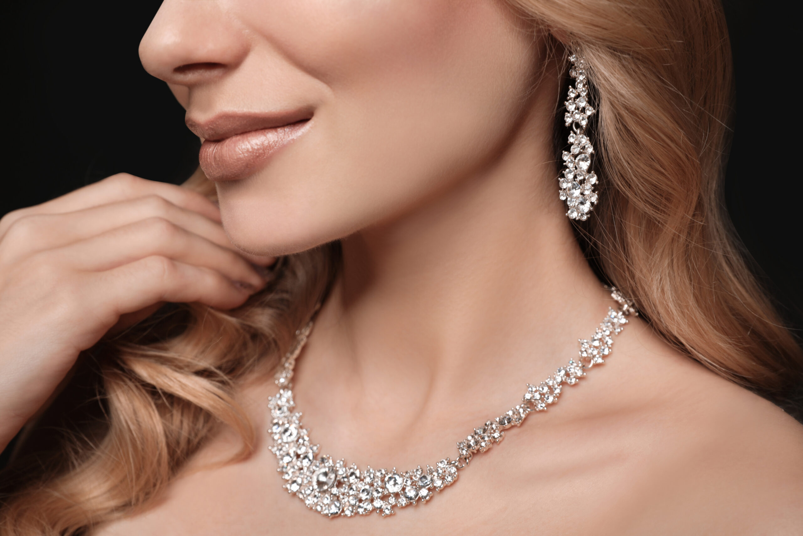 Beautiful young woman with elegant jewelry on dark background, closeup